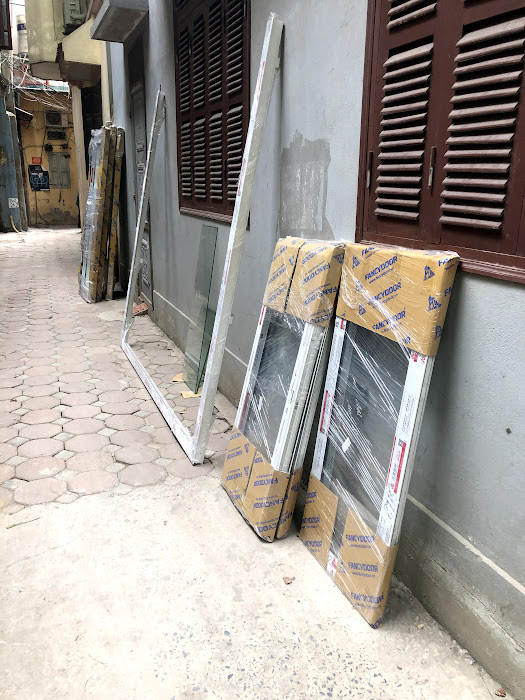 Cửa nhôm kính và khung nhôm kính mới được đóng gói đặt ngoài hành lang chuẩn bị lắp đặt